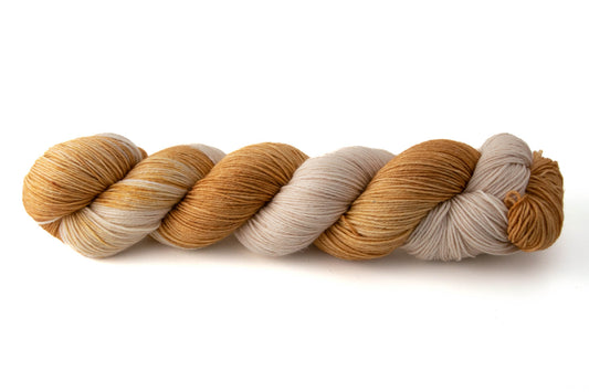 A skein of variegated brown and tan hand-dyed wool yarn.