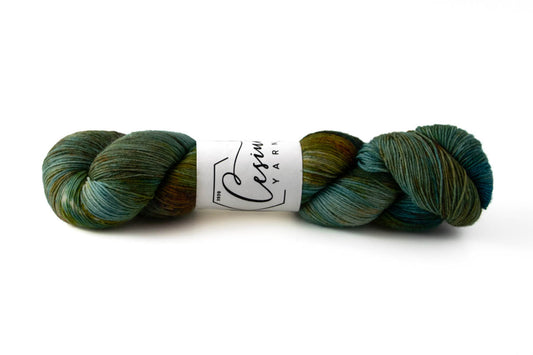 A teal, green, and rust skein of hand-dyed wool yarn.