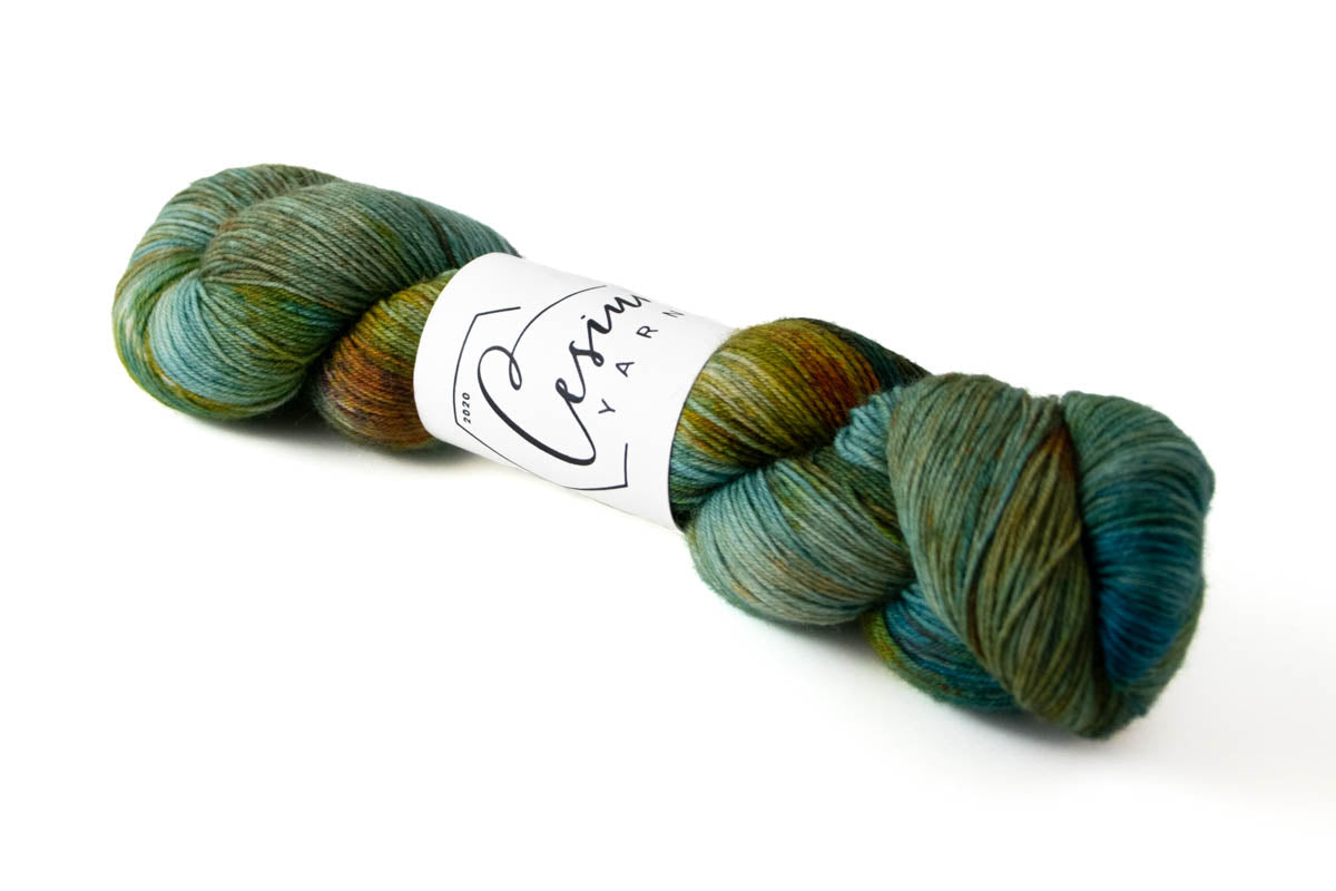 A teal, green, and rust skein of hand-dyed wool yarn.