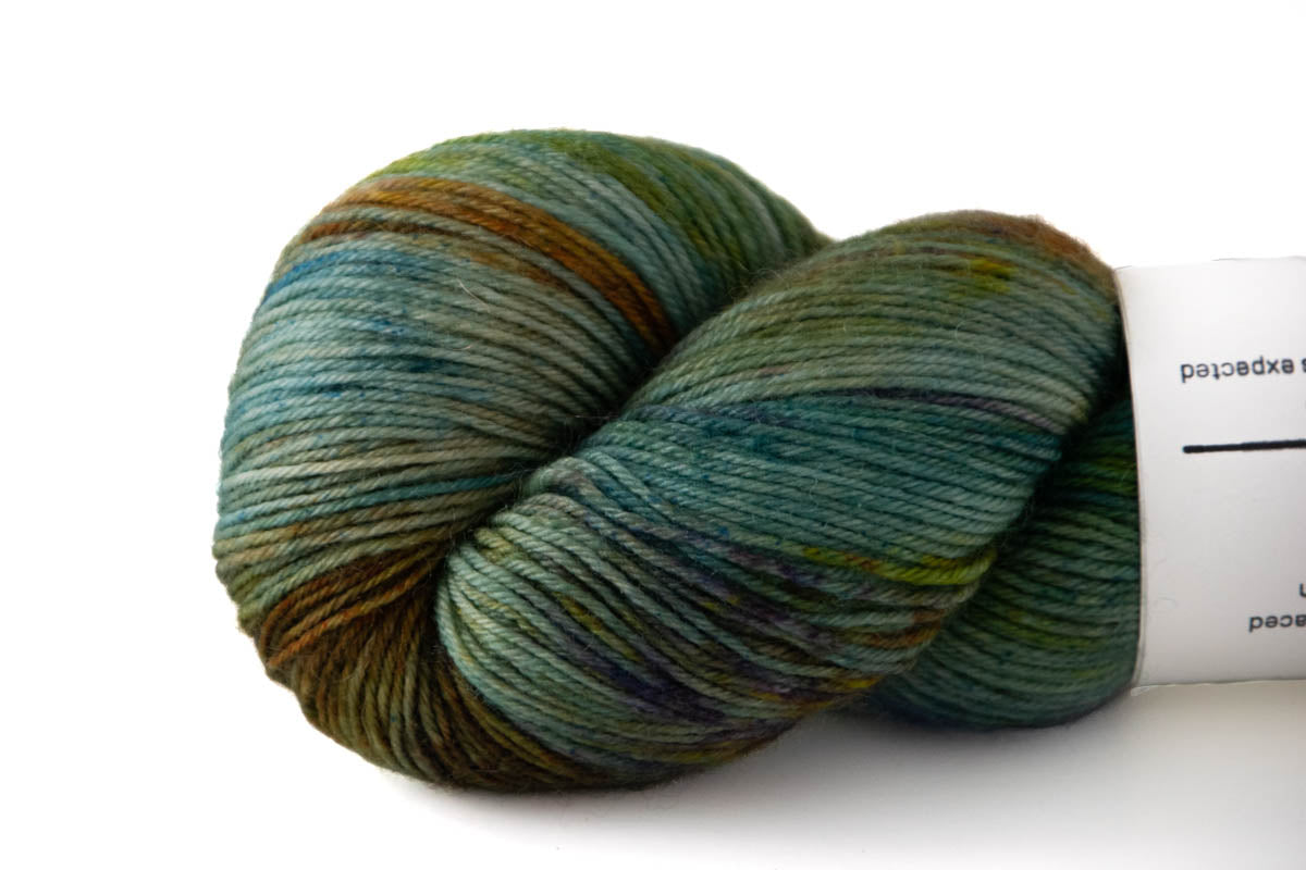 Close-up of the variegated texture of the yarn with sections of green, aqua, rust, and speckles of dark blue.