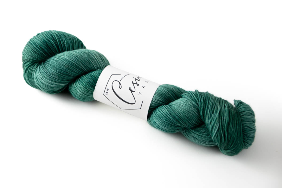 A green tonal hand-dyed wool yarn with blue undertones.