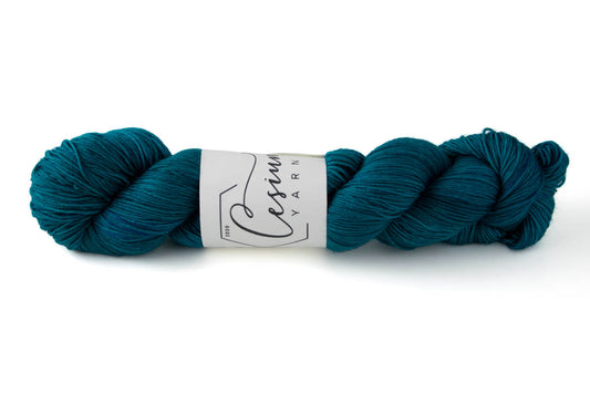 A skein of tonal teal hand-dyed wool yarn.