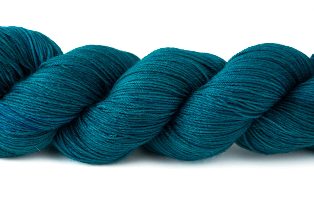 A closeup on the tonal qualities of the skein, which include swathes of teal and small sections of navy.