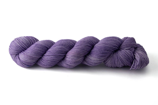 A skein of tonal purple hand-dyed wool yarn.