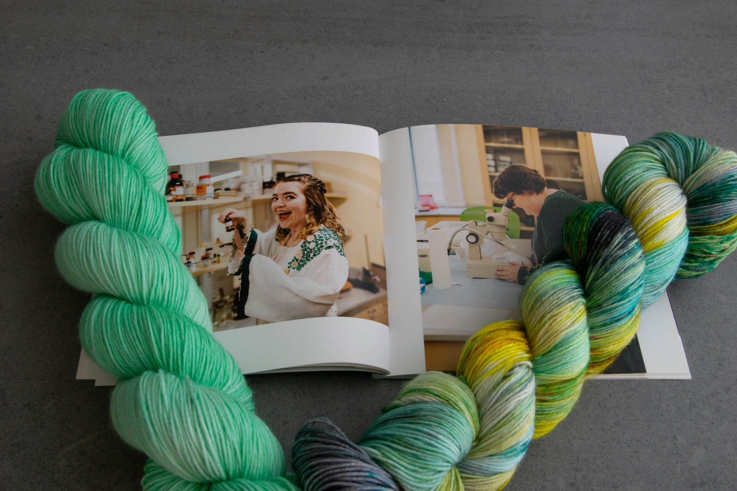 A skein of aqua Dana with its complementary aqua, yellow, green, and gray variegated colorway and graduation photos of Cat and Penny.