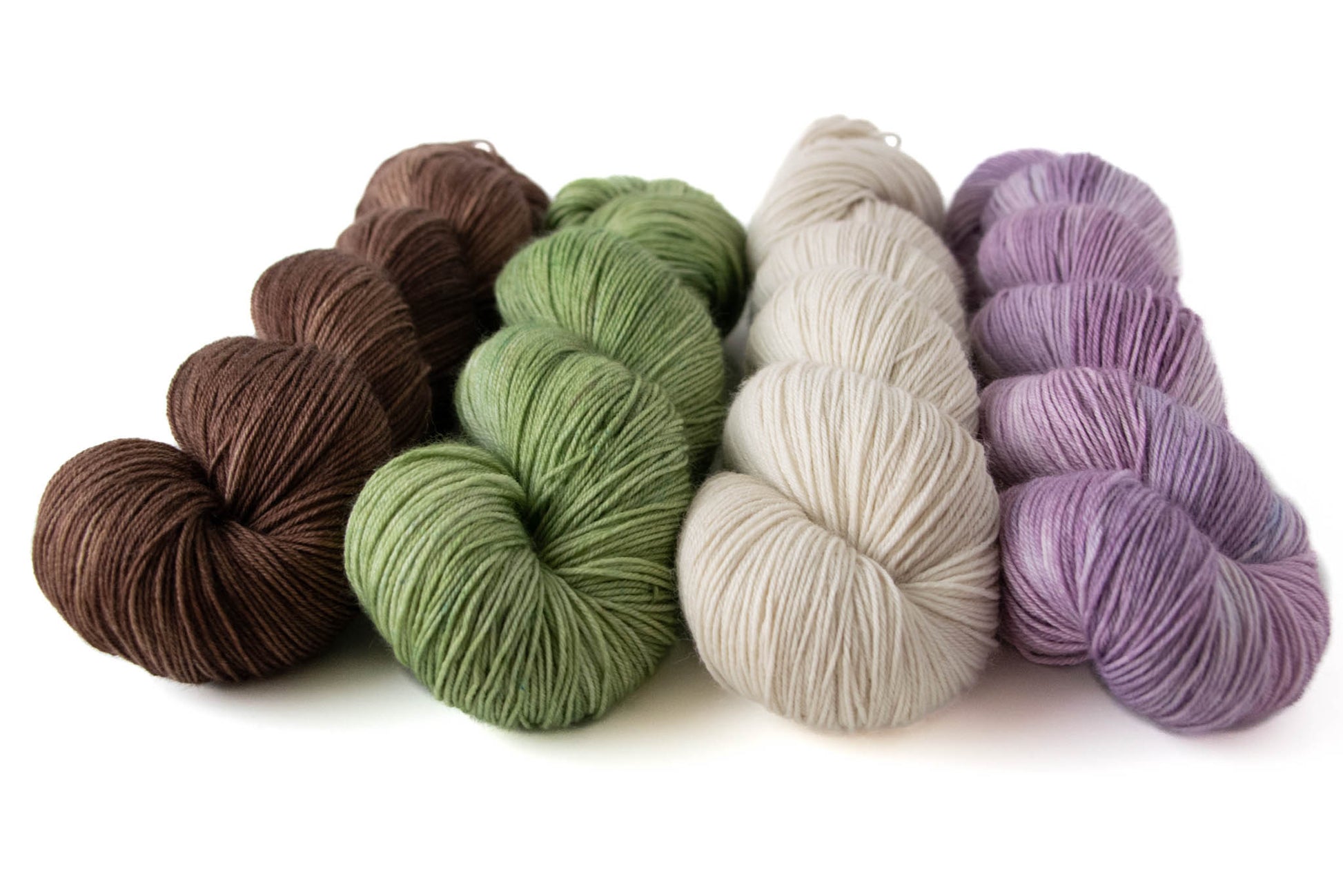 The four tonal colorways in the Murder, She Knit collection: brown, green, cream, and purple.