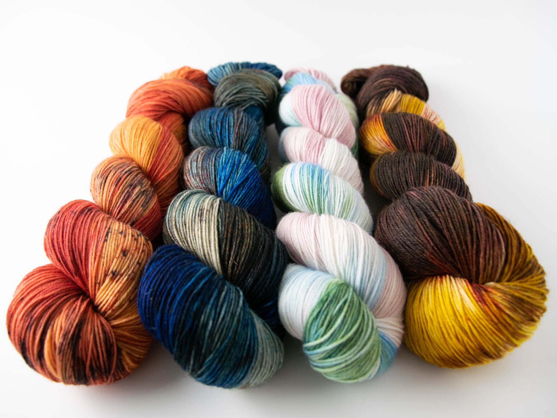 The four variegated colorways in the collection: red and orange; blue, brown, and orange; green, blue, pink, and white; brown, yellow, and orange.