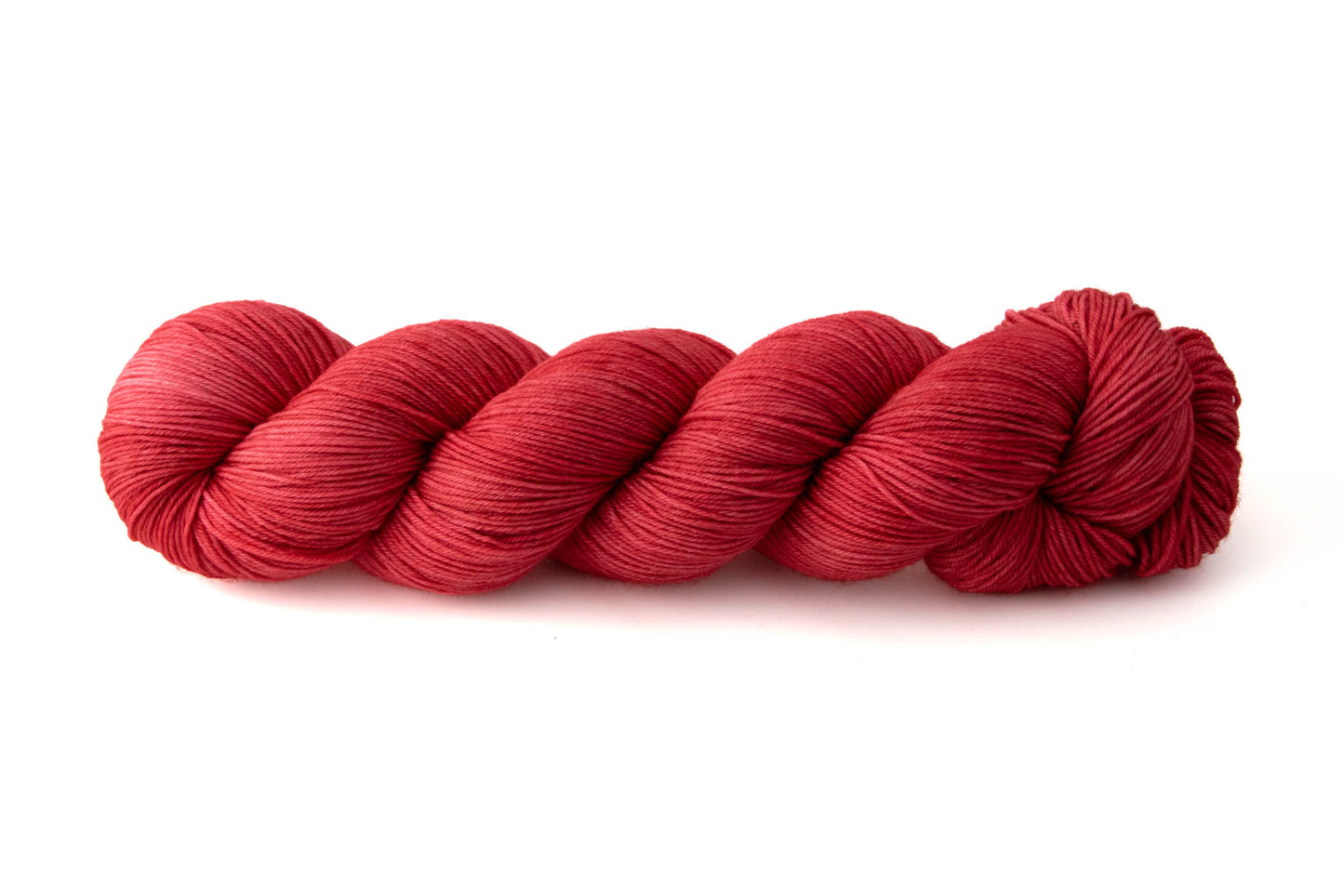 A bright red skein of tonal hand-dyed wool yarn.