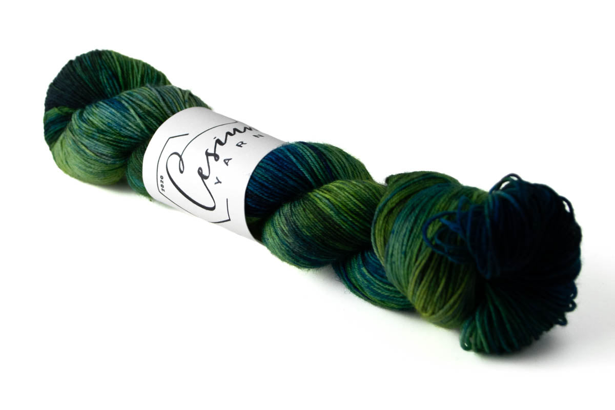 A green and blue variegated skein of hand-dyed wool yarn.