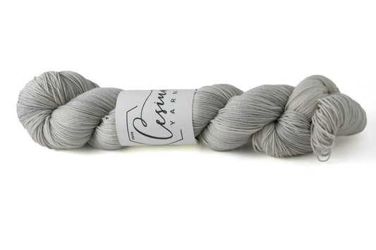 A light gray skein of hand-dyed wool yarn.