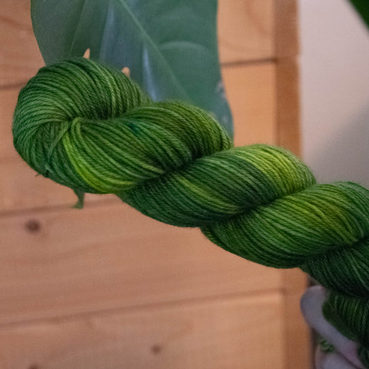 A bright green tonal skein of hand-dyed wool yarn.