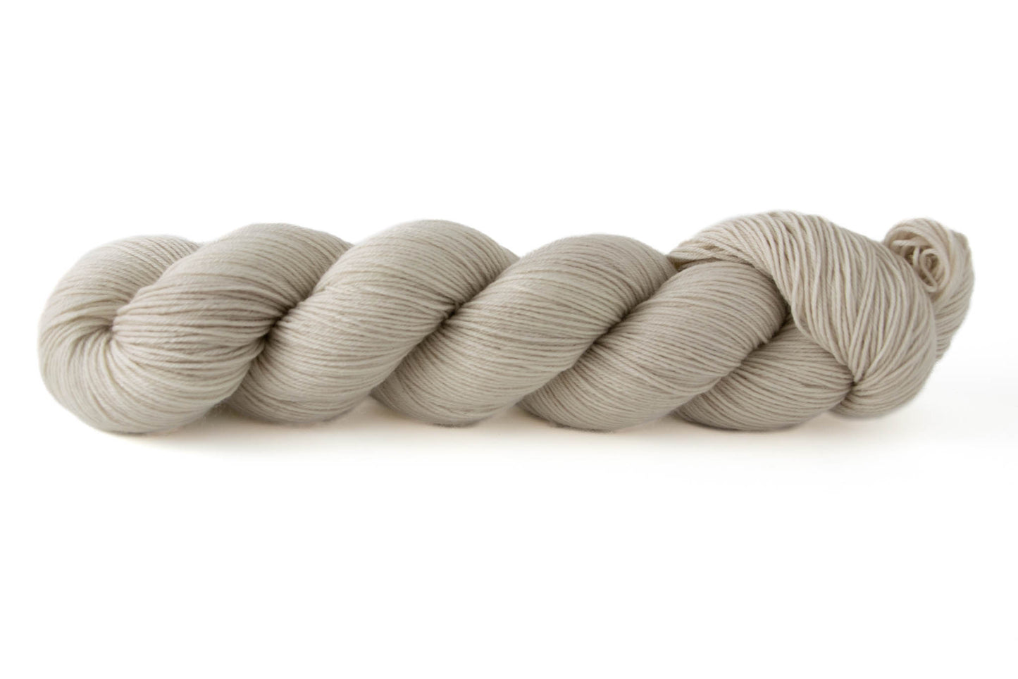 A bone white, cream skein of hand-dyed wool yarn.