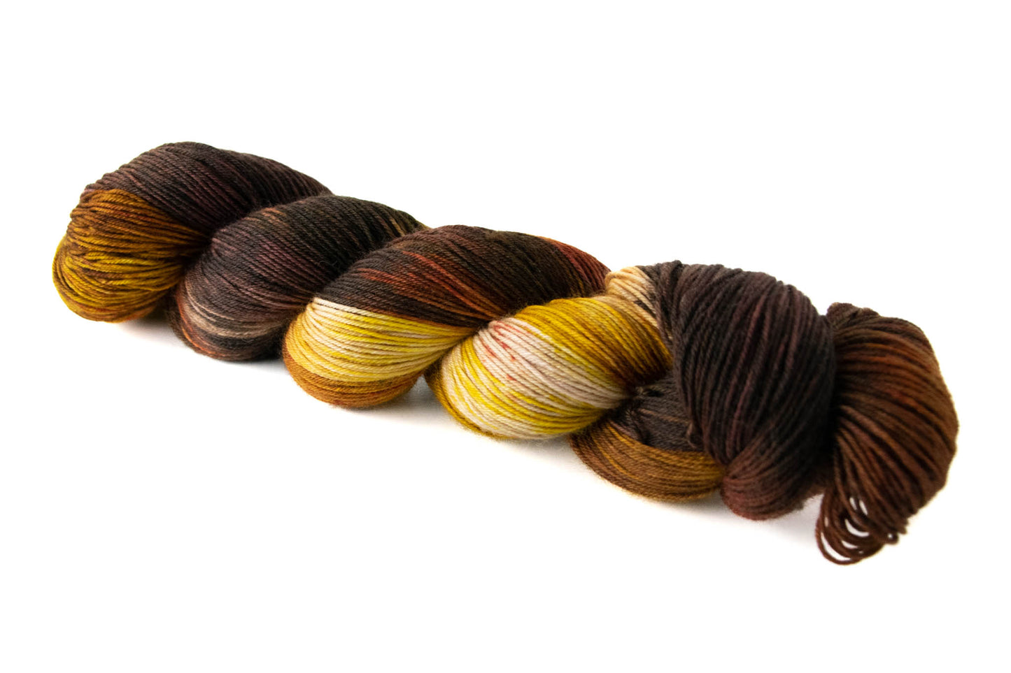 A skein of brown and yellow variegated hand dyed wool yarn with red speckles.