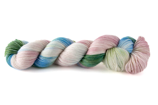 A skein of variegated green, blue, pink, and white hand-dyed wool yarn.