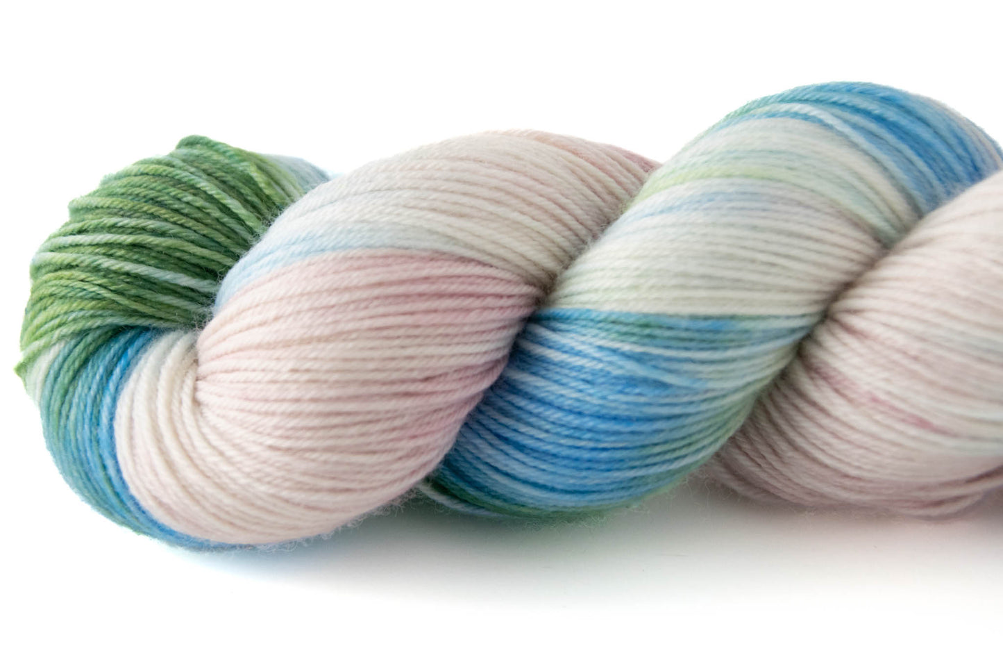 A closeup on the end of the green, blue, pink, and white hand-dyed wool yarn.