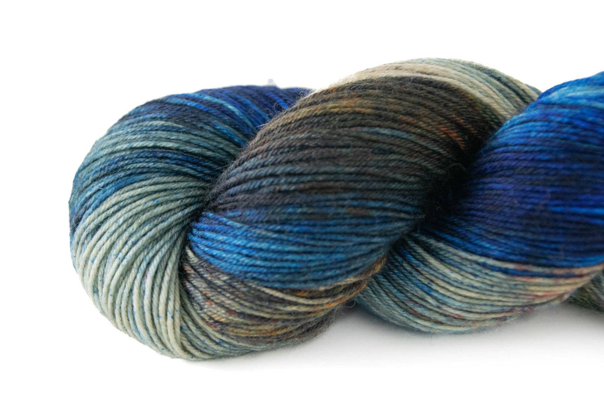 Closeup on end of skein with blue and brown sections and two sections of tan, one with blue speckles and one with orange and brown speckles.