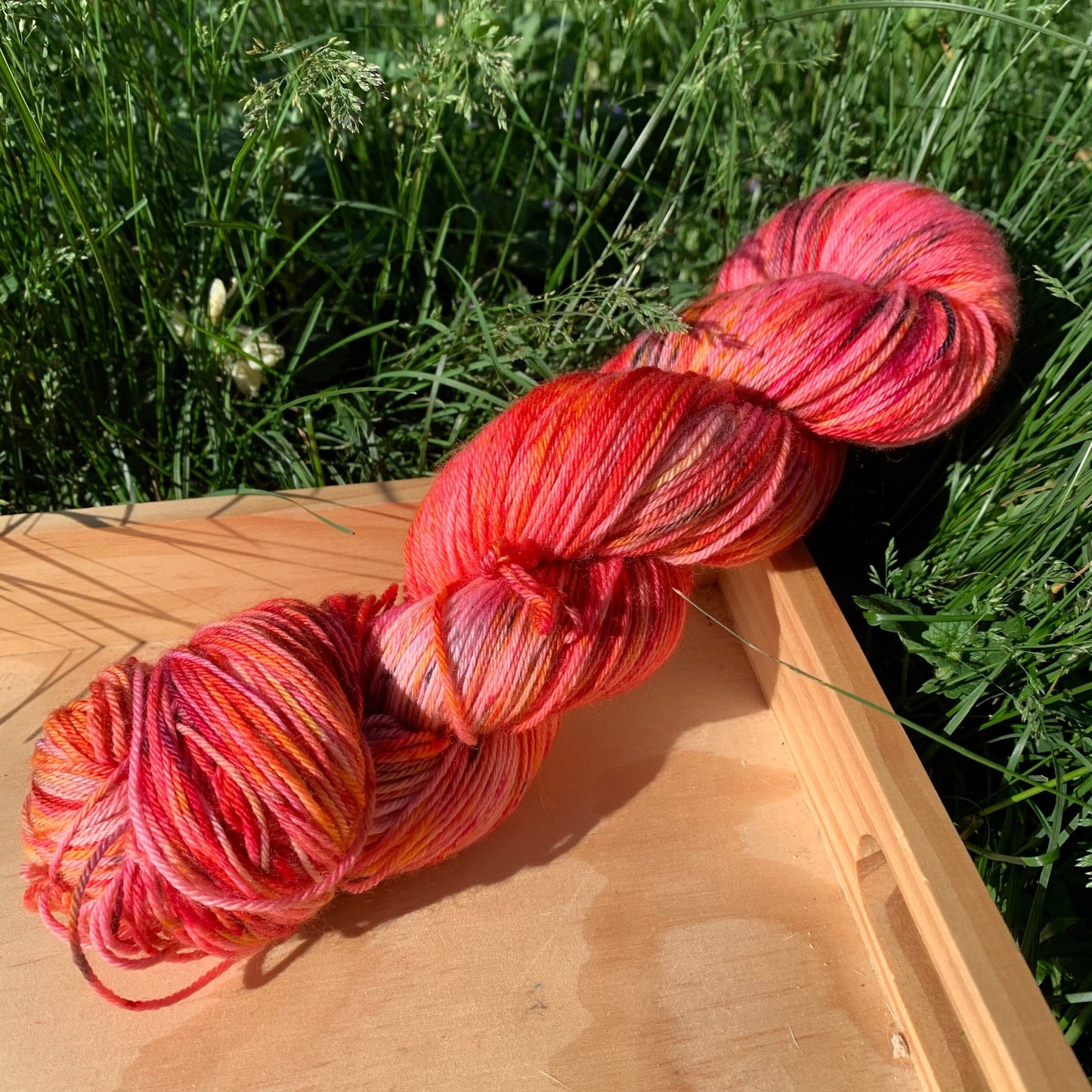 A skein of black and pink speckled red hand-dyed yarn.