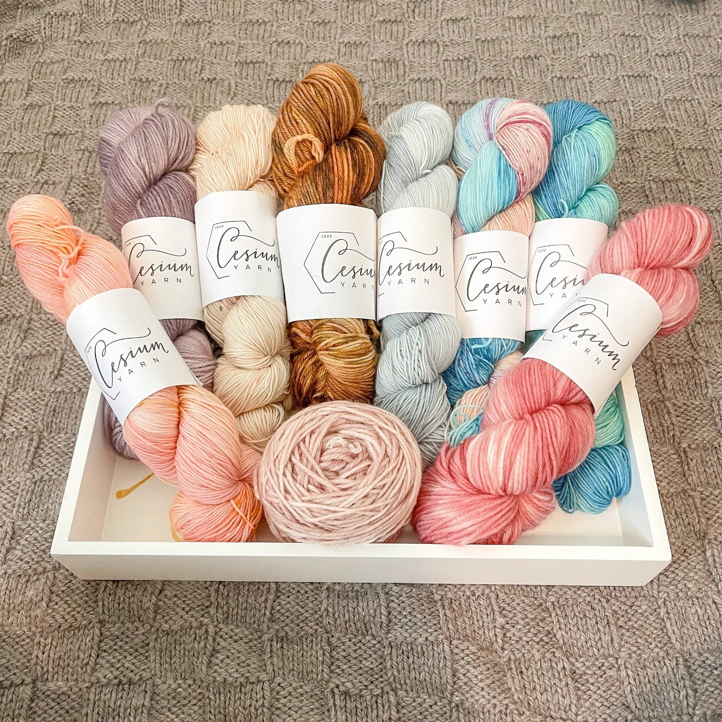 Skeins in the nine colorways in the Aura collection: peach, purple, tan, brown, blue, aqua and pink, aqua and green, bright pink, and pale pink.