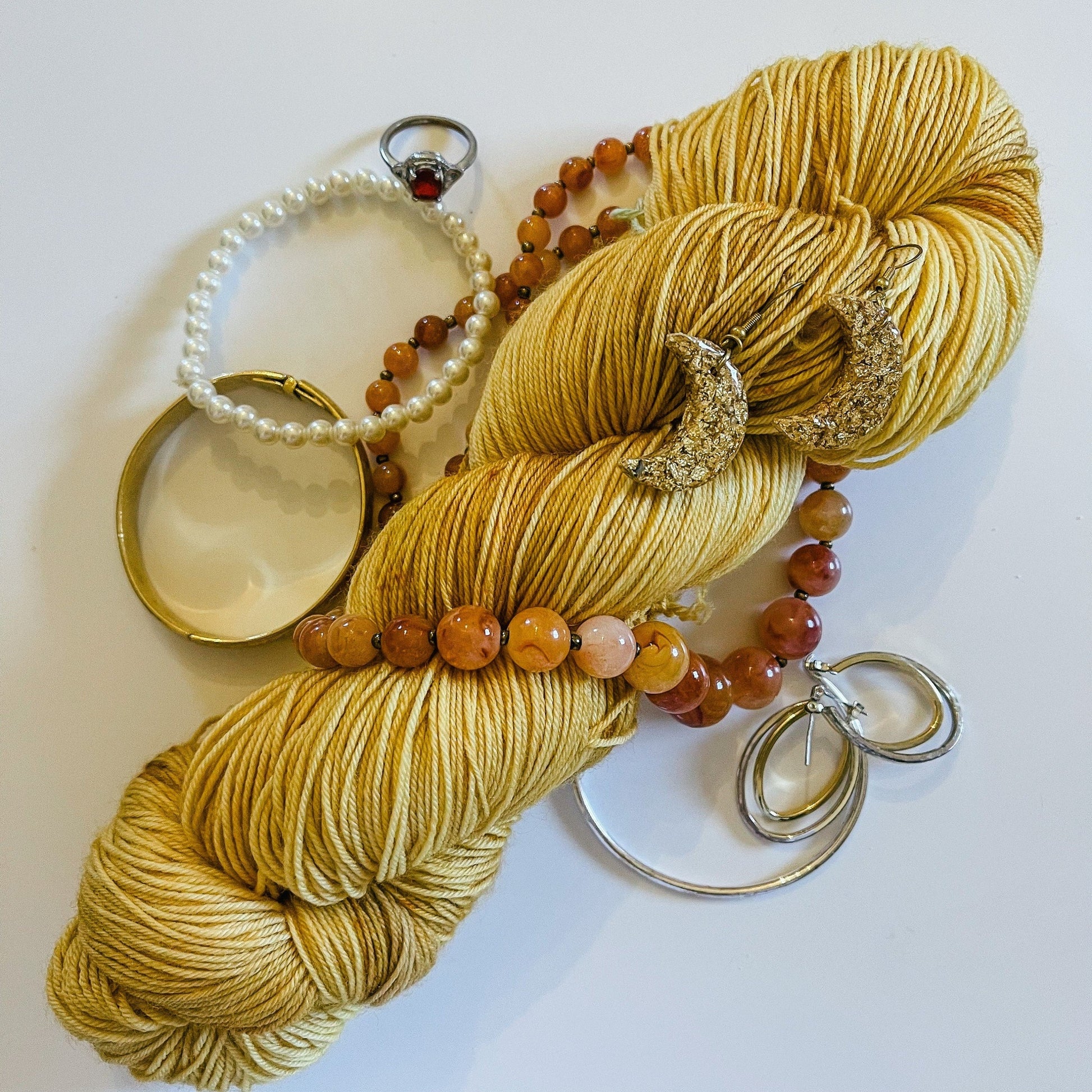 Yellow hand-dyed Merino yarn with amber, gold, and silver jewels around it