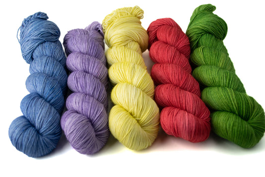 Five skeins of tonal hand-dyed wool yarn in blue, purple, yellow, red, and green.